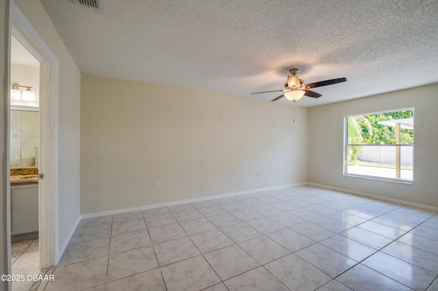 spare room with light tile patterned floors, a textured ceiling, a ceiling fan, and baseboards