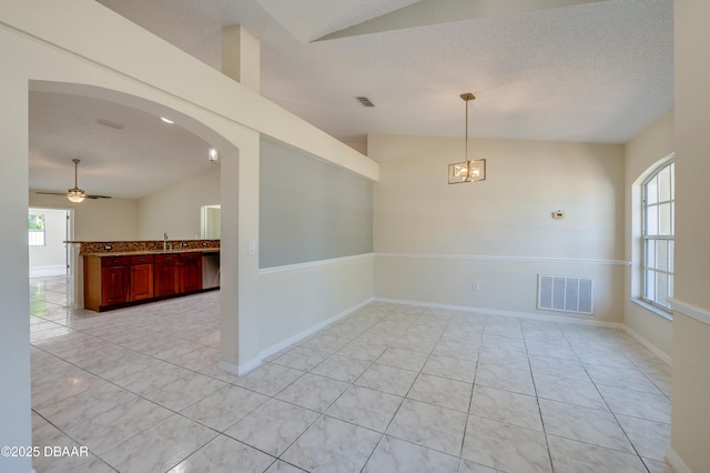 empty room with light tile patterned flooring, visible vents, lofted ceiling, and arched walkways