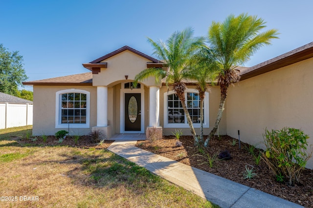view of front of house with a front lawn, fence, and stucco siding