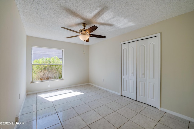 unfurnished bedroom featuring light tile patterned floors, ceiling fan, a textured ceiling, and a closet