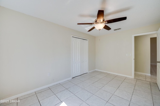 empty room featuring baseboards, visible vents, light tile patterned floors, and ceiling fan