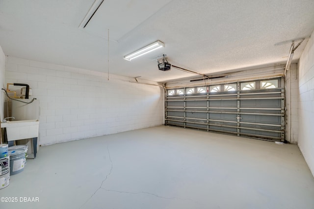 garage featuring a garage door opener and concrete block wall