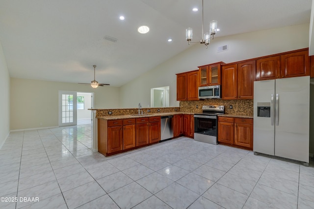 kitchen featuring light stone countertops, decorative backsplash, stainless steel appliances, vaulted ceiling, and a peninsula