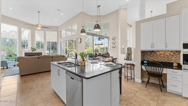 kitchen featuring tasteful backsplash, dark countertops, a sink, and stainless steel dishwasher