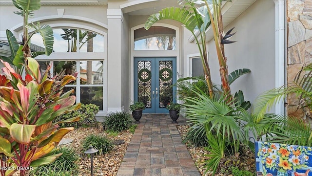 view of exterior entry featuring stucco siding and french doors