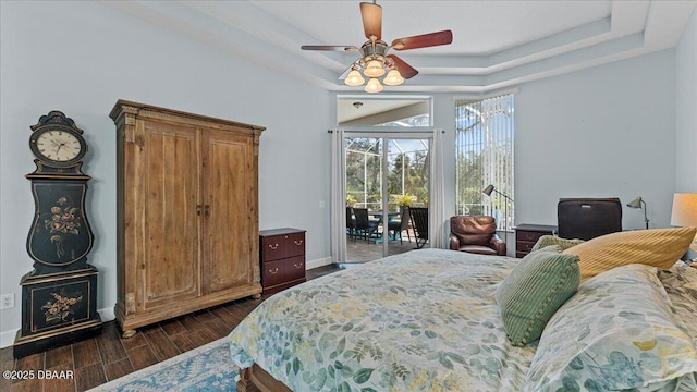 bedroom with access to exterior, wood finish floors, a raised ceiling, a sunroom, and baseboards