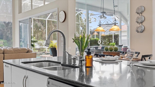 kitchen with a ceiling fan, white cabinets, a sink, dark stone countertops, and dishwasher