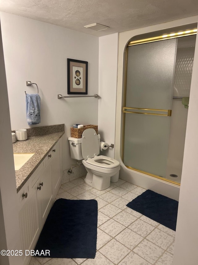 full bath featuring vanity, a shower stall, toilet, and a textured ceiling