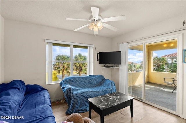 living room with ceiling fan, a healthy amount of sunlight, light hardwood / wood-style floors, and a textured ceiling