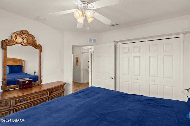 bedroom featuring hardwood / wood-style floors, a textured ceiling, a closet, and ceiling fan