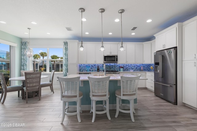 418 Good Life Way, Daytona Beach, FL 32124 - kitchen with a kitchen island with sink, hanging light fixtures, white cabinets, and appliances with stainless steel finishes