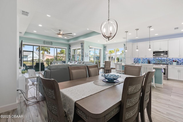 418 Good Life Way, Daytona Beach, FL 32124 - dining room featuring ceiling fan with notable chandelier, a raised ceiling, and light hardwood / wood-style floors
