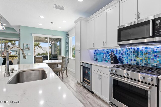 418 Good Life Way, Daytona Beach, FL 32124 - kitchen with sink, stainless steel appliances, wine cooler, light stone countertops, and white cabinets