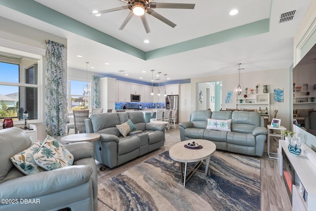 418 Good Life Way, Daytona Beach, FL 32124 - living room with ceiling fan with notable chandelier, a raised ceiling, and light wood-type flooring