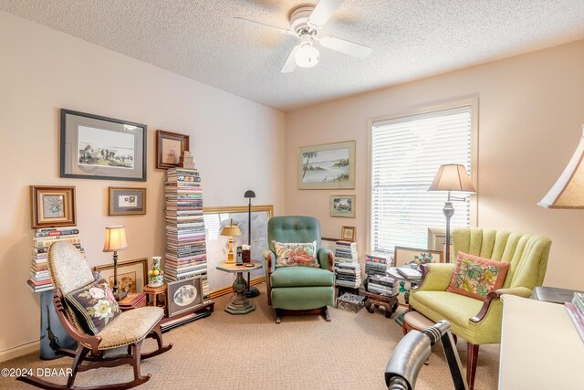 living area featuring carpet, a textured ceiling, and ceiling fan