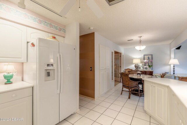 kitchen with white refrigerator with ice dispenser, white cabinetry, a textured ceiling, hanging light fixtures, and ceiling fan