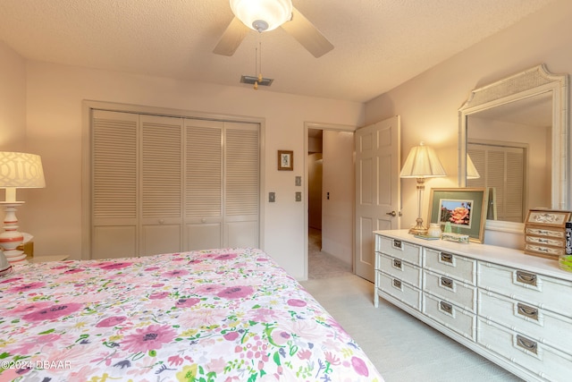 carpeted bedroom with a textured ceiling, ceiling fan, and a closet