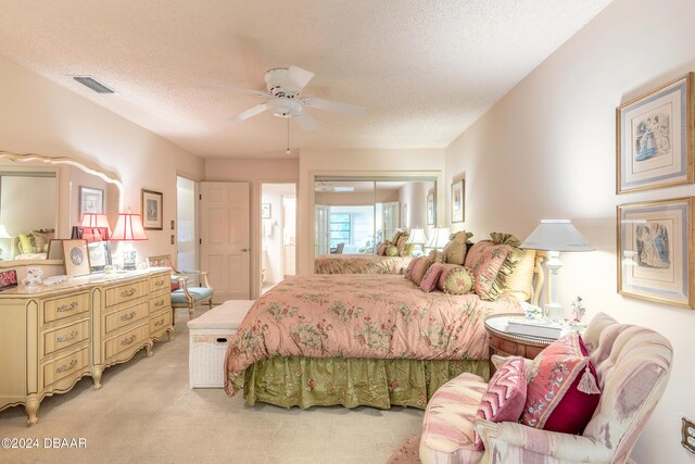 carpeted bedroom featuring a closet, a textured ceiling, and ceiling fan