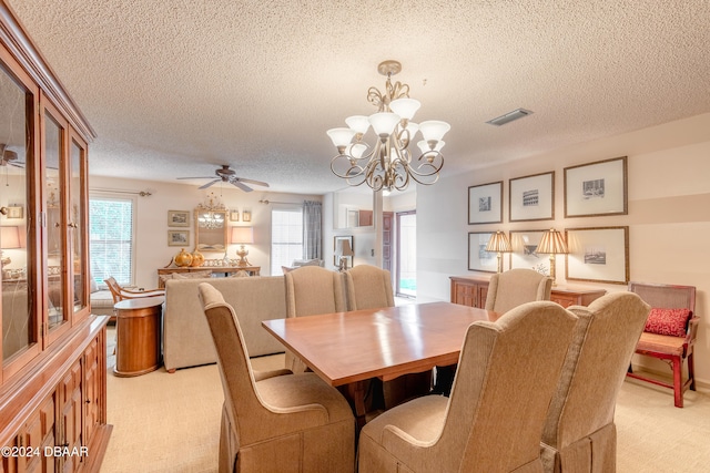 carpeted dining room with a textured ceiling, a healthy amount of sunlight, and ceiling fan with notable chandelier