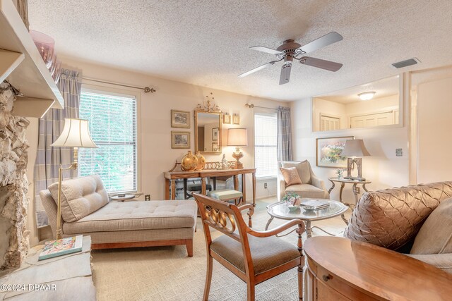 living area with ceiling fan, a healthy amount of sunlight, and a textured ceiling