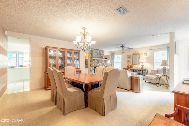 carpeted dining area with a fireplace, ceiling fan with notable chandelier, and a textured ceiling