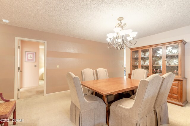 dining area featuring a textured ceiling, light carpet, and a chandelier