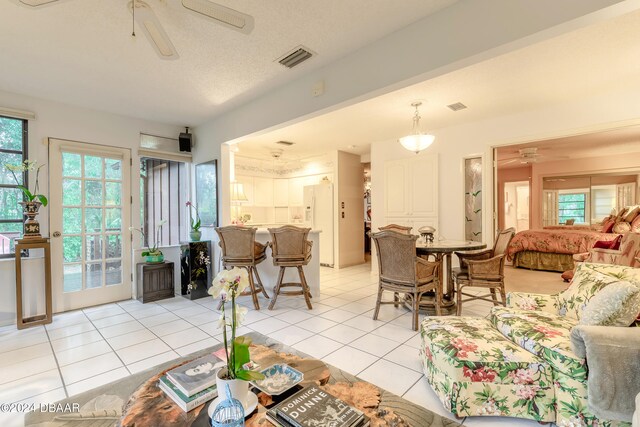 living room featuring a textured ceiling, light tile patterned floors, ceiling fan, and plenty of natural light