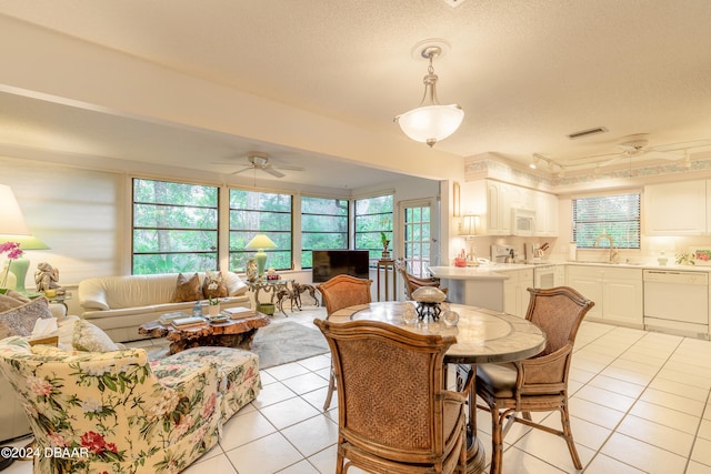 tiled dining space featuring a textured ceiling, ceiling fan, and sink