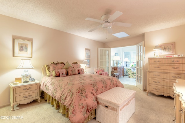 bedroom featuring a textured ceiling, light colored carpet, and ceiling fan