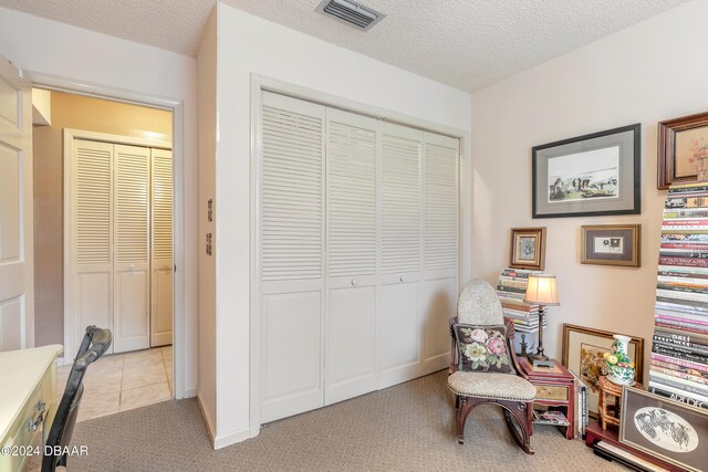 living area with a textured ceiling and light carpet