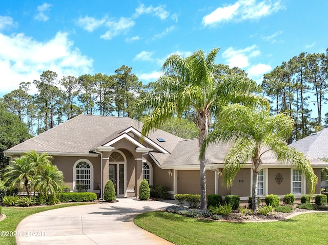 850 Westlake Dr, Ormond Beach, FL 32174 - ranch-style house featuring curved driveway, a front lawn, an attached garage, a shingled roof, and stucco siding