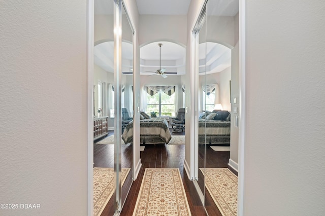 850 Westlake Dr, Ormond Beach, FL 32174 - hall featuring a textured wall, baseboards, a tray ceiling, arched walkways, and dark wood finished floors