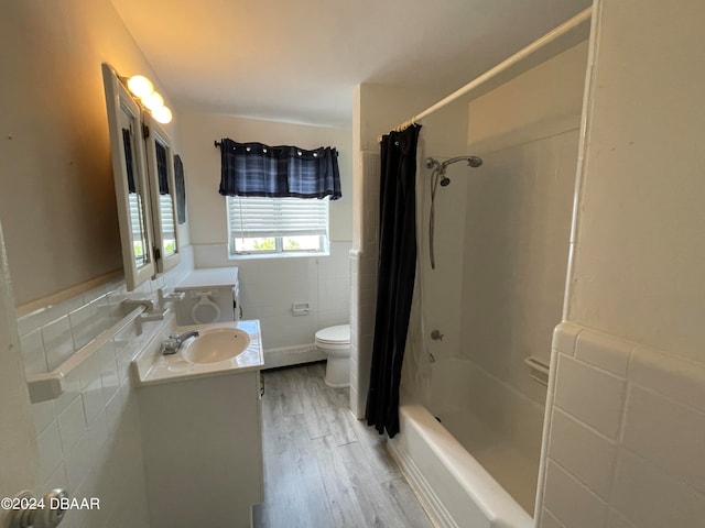 full bathroom with tile walls, shower / bath combination with curtain, vanity, hardwood / wood-style flooring, and toilet