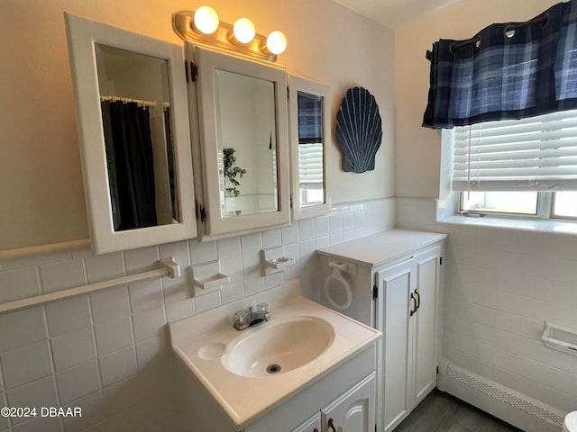 bathroom with baseboard heating, vanity, and tile walls