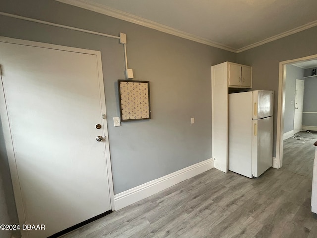 kitchen featuring ornamental molding, light wood-type flooring, and white refrigerator