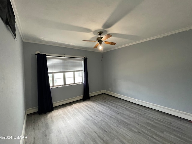 spare room with hardwood / wood-style flooring, ceiling fan, baseboard heating, and crown molding