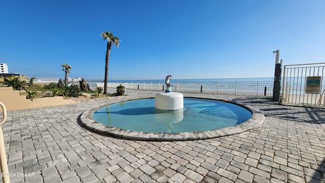 view of swimming pool featuring a water view and a patio