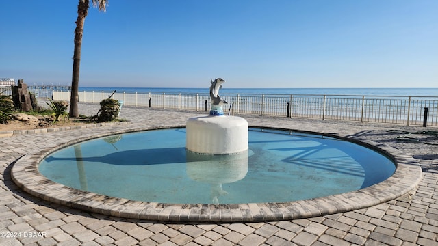 view of swimming pool featuring a view of the beach and a water view