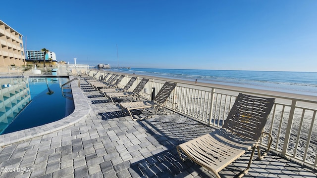 view of community with a beach view, a water view, a patio, and a pool