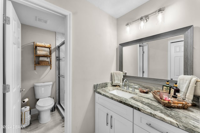 bathroom with hardwood / wood-style floors, an enclosed shower, vanity, and toilet