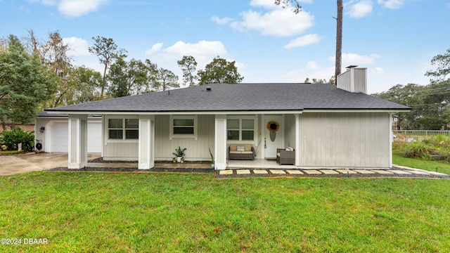 back of property with a garage, a porch, and a yard