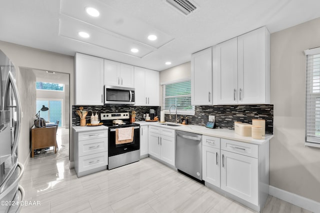 kitchen with stainless steel appliances, a healthy amount of sunlight, and white cabinetry