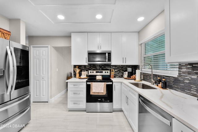 kitchen with light stone counters, white cabinets, sink, backsplash, and appliances with stainless steel finishes