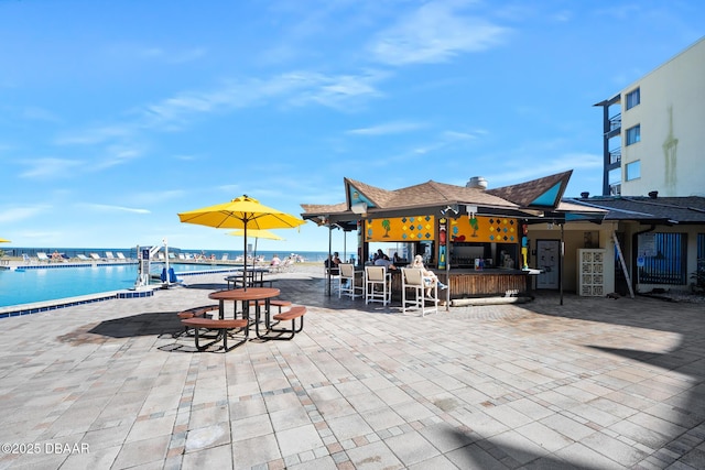 view of patio with exterior bar and a water view