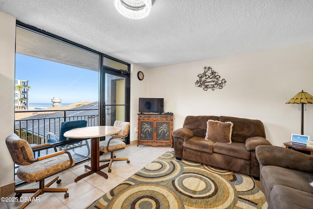 living room featuring light tile patterned floors, a wall of windows, a textured ceiling, and a water view