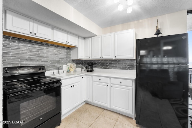 kitchen with sink, black appliances, light tile patterned floors, decorative backsplash, and white cabinets