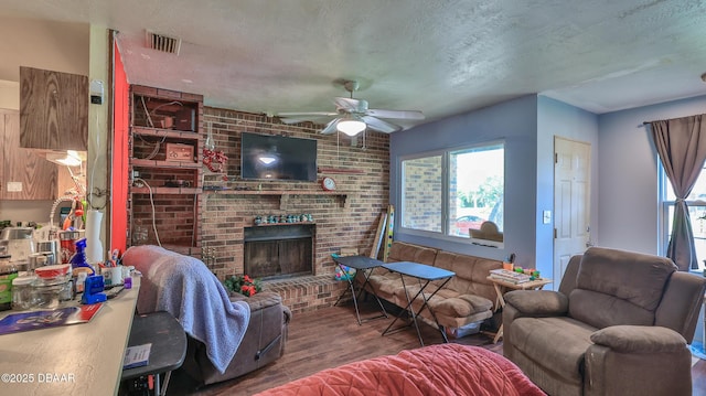living area with ceiling fan, wood finished floors, a fireplace, and a textured ceiling