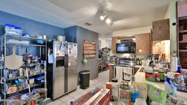 kitchen with stainless steel appliances, light tile patterned floors, a sink, light countertops, and track lighting