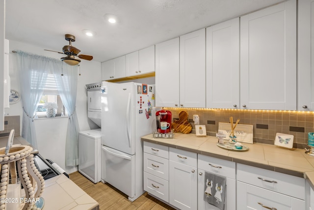 456 Bouchelle Dr Unit 104, New Smyrna Beach, FL 32169 - kitchen with tasteful backsplash, white cabinets, freestanding refrigerator, and a ceiling fan