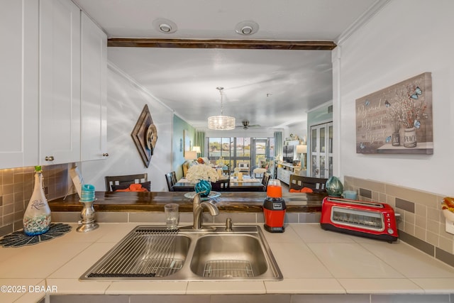 456 Bouchelle Dr Unit 104, New Smyrna Beach, FL 32169 - kitchen featuring backsplash, tile countertops, crown molding, and a sink